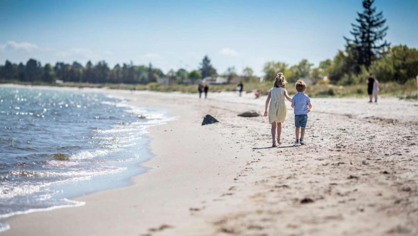 Barn går langs Saksild Strand i regionen Kystlandet, Danmark