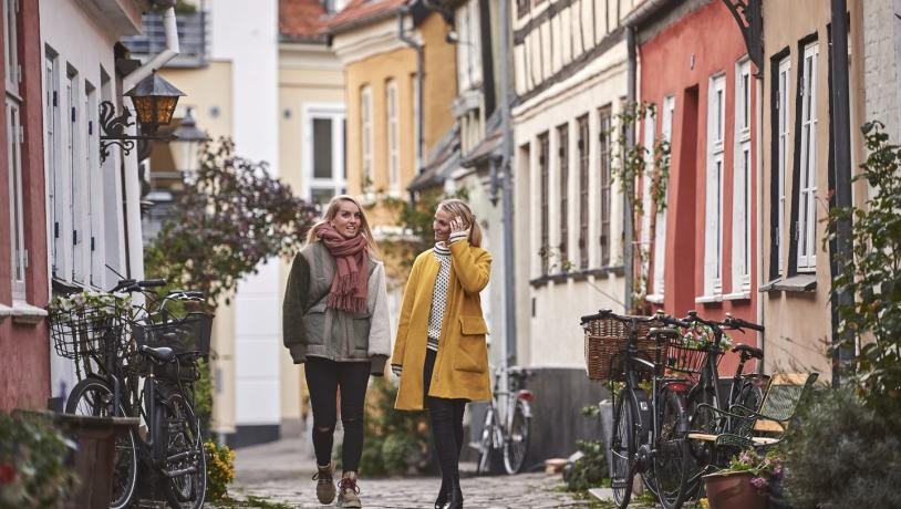 To kvinner går i Aalborgs gater på høsten