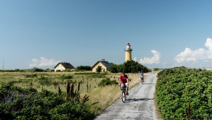 Fietsers passeren de Omø Fyr vuurtoren op het Deense eiland Omø