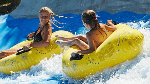 Two women on floating donuts on a water slide