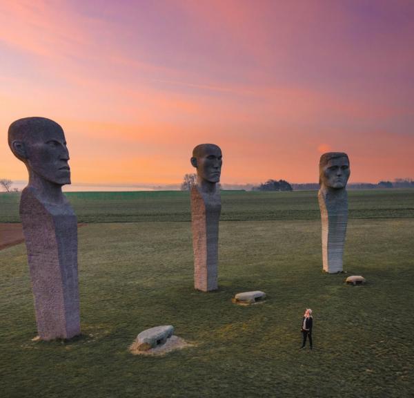 Person looking at stone sculptures Dodekalitten during sunset on Lolland-Falster, Denmark