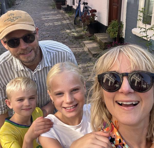 Lisa med familj ler i kameran på en gågåta i bakgrunden